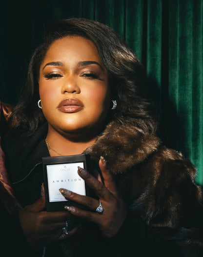 Woman holding a candle box with a dark green background.